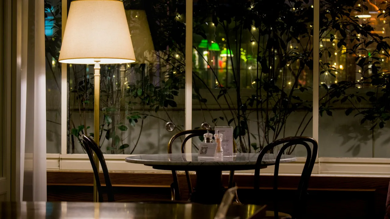 An empty table set for two by a window at night
